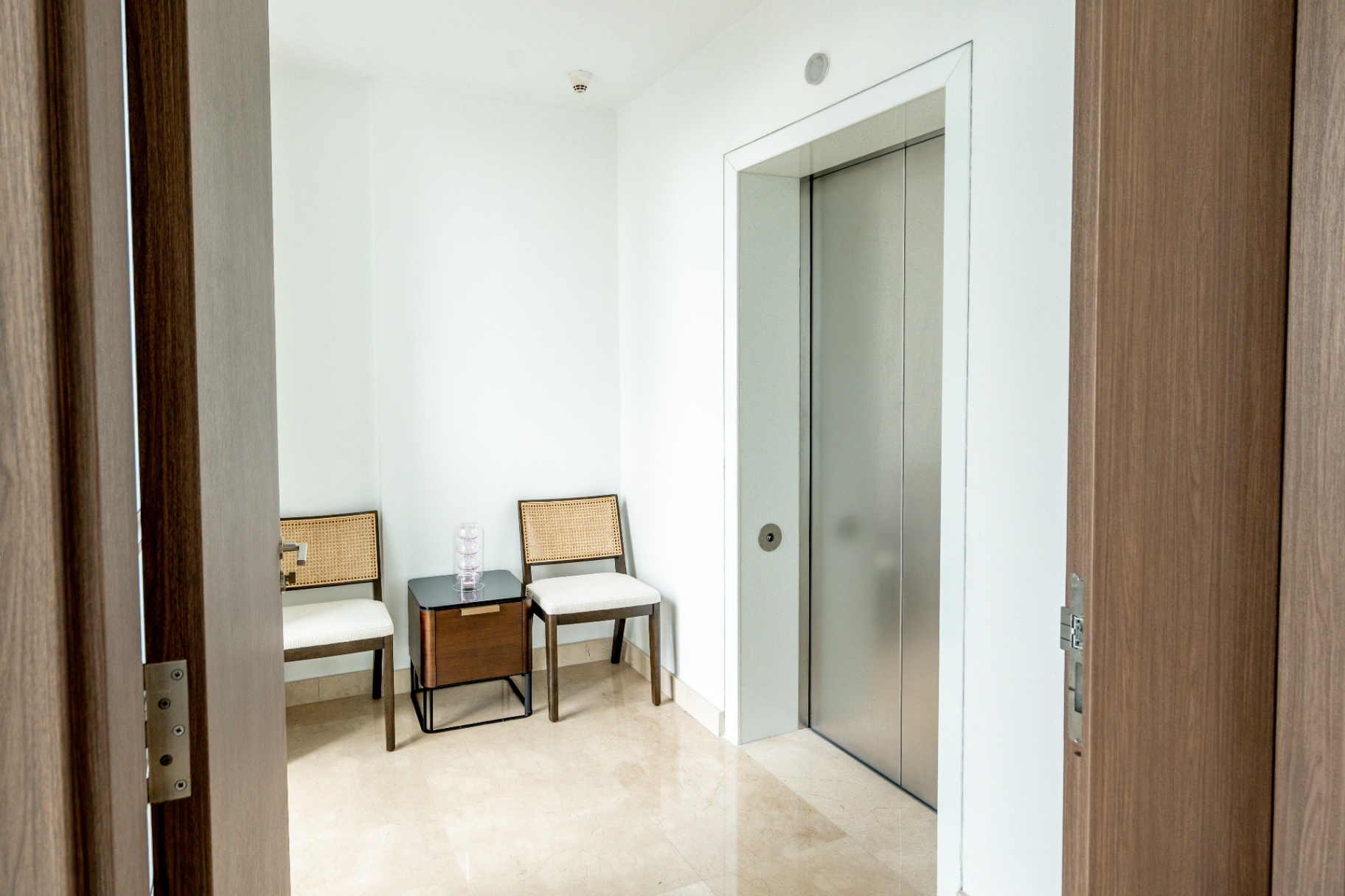 Draycott 8 — private lift lobby with cane chairs and marble flooring